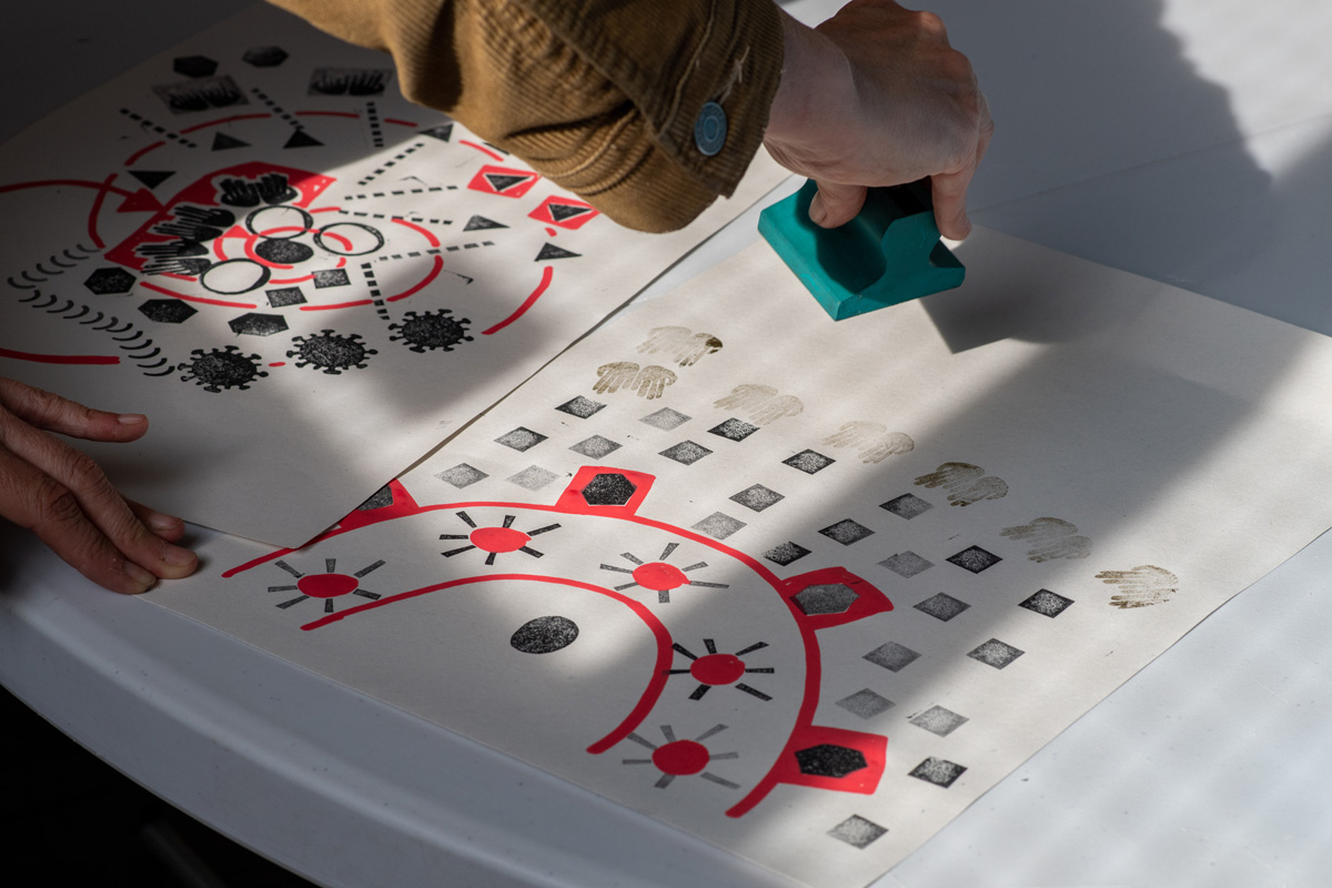 hand using block prints to create a map using symbols